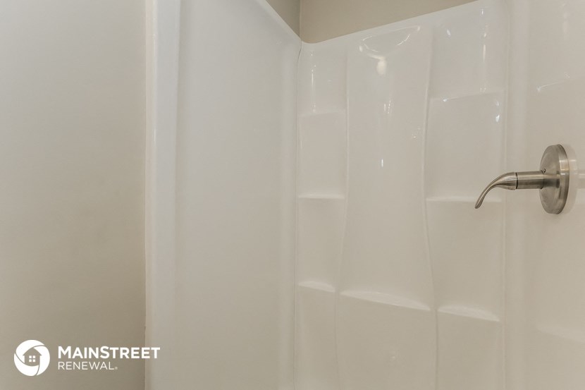 a walk in shower in a bathroom with a white shower curtain