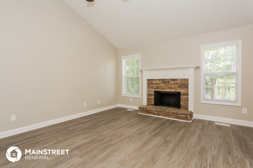 the living room with wood floors and a fireplace