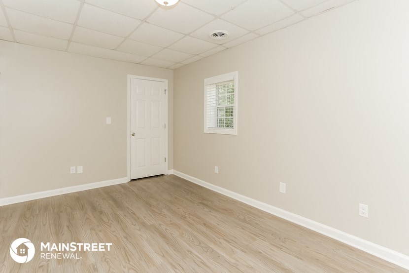 the upstairs bedroom with wood flooring and a white door