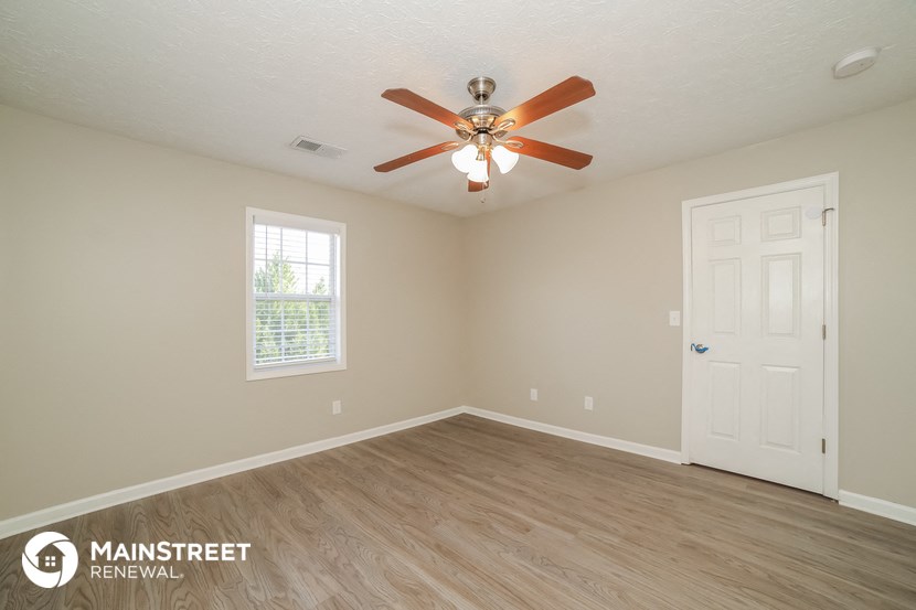 the spacious living room with ceiling fan and wood flooring