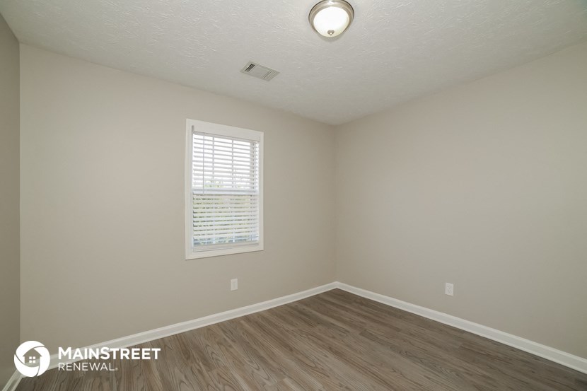 the interior of an empty room with wood flooring and a window