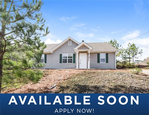 a small gray house with a yard and trees