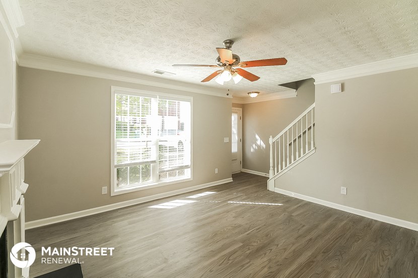 a living room with a ceiling fan and a staircase