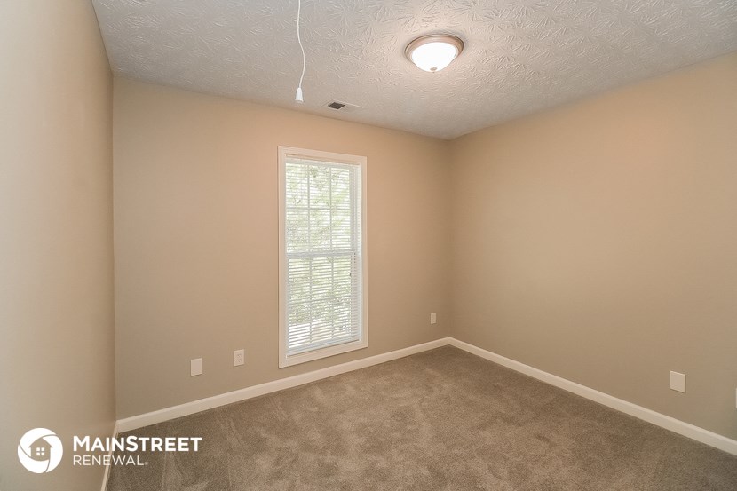 the interior of a bedroom with carpet and a window