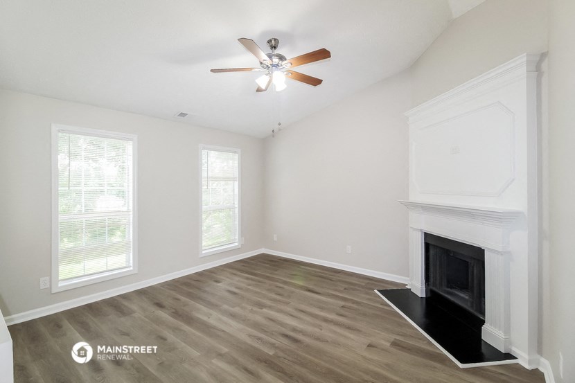 a living room with a fireplace and a ceiling fan