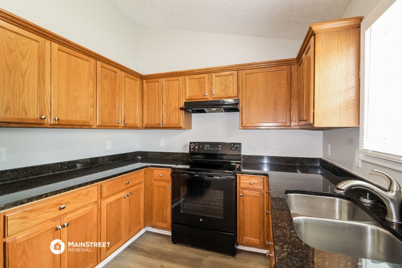 a kitchen with wood cabinets and black appliances and a sink
