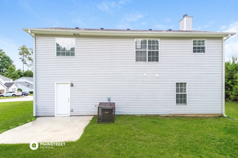 a side view of a white house with a driveway and grass