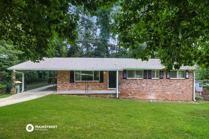 the front of a brick house with a lawn and trees