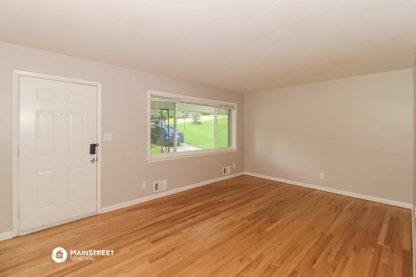 the living room of a house with wooden floors and a window