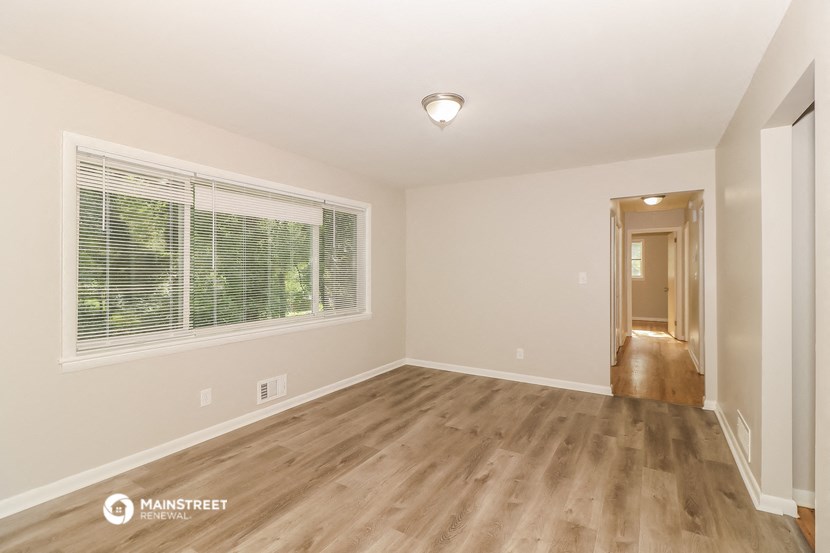 the spacious living room with a large window and wood flooring