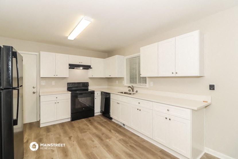 a renovated kitchen with white cabinets and black appliances