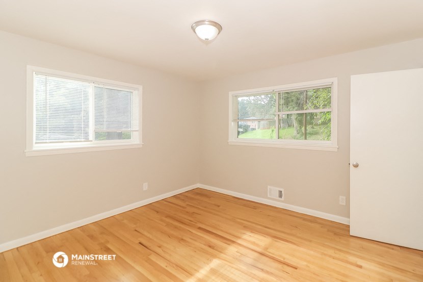 the living room of a house with wood floors and two windows