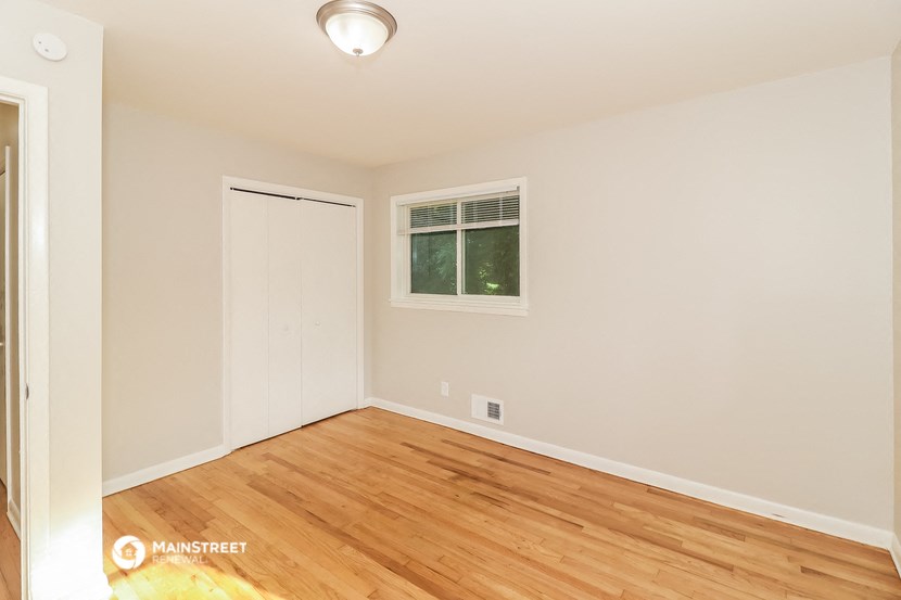 a bedroom with wood flooring and a door to a closet