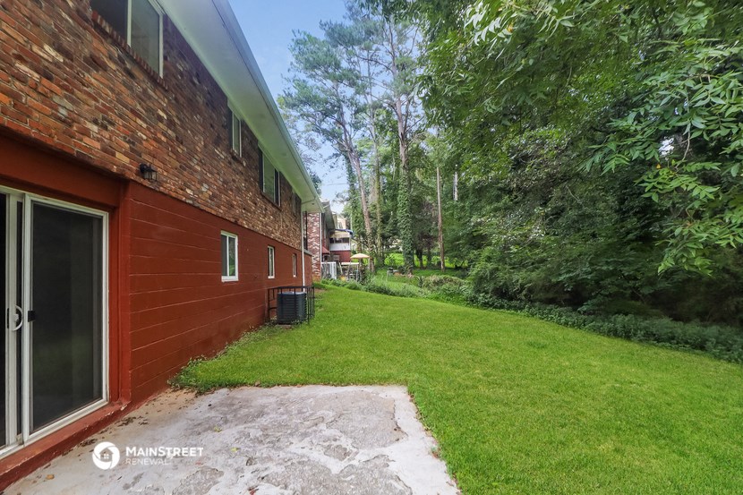 a backyard with a red brick house and a lawn and trees
