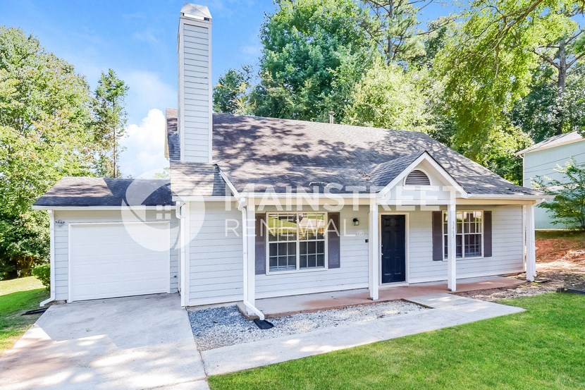 a small white house with a porch and a driveway