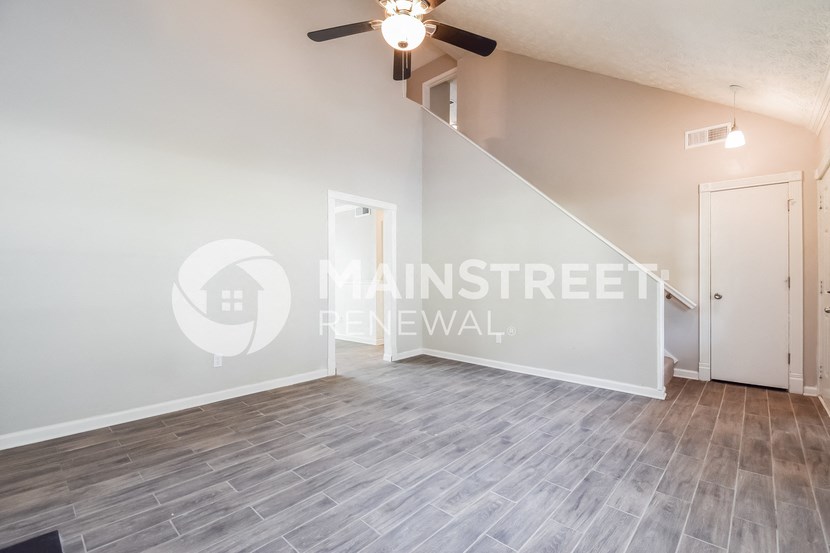 a renovated living room with a ceiling fan and hard wood floors