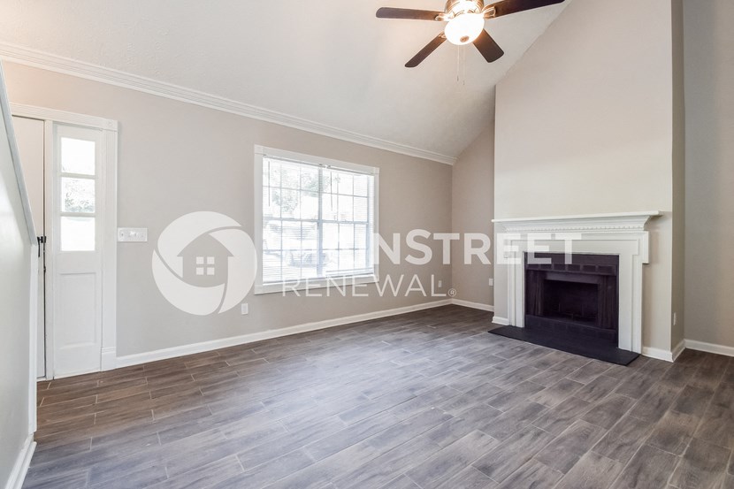 a living room with a fireplace and a ceiling fan