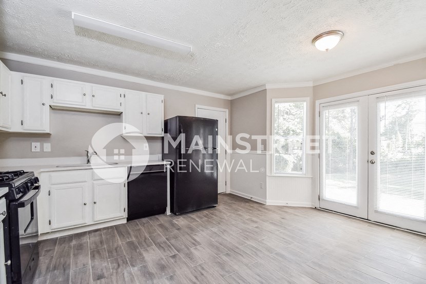 a renovated kitchen with white cabinets and a black refrigerator