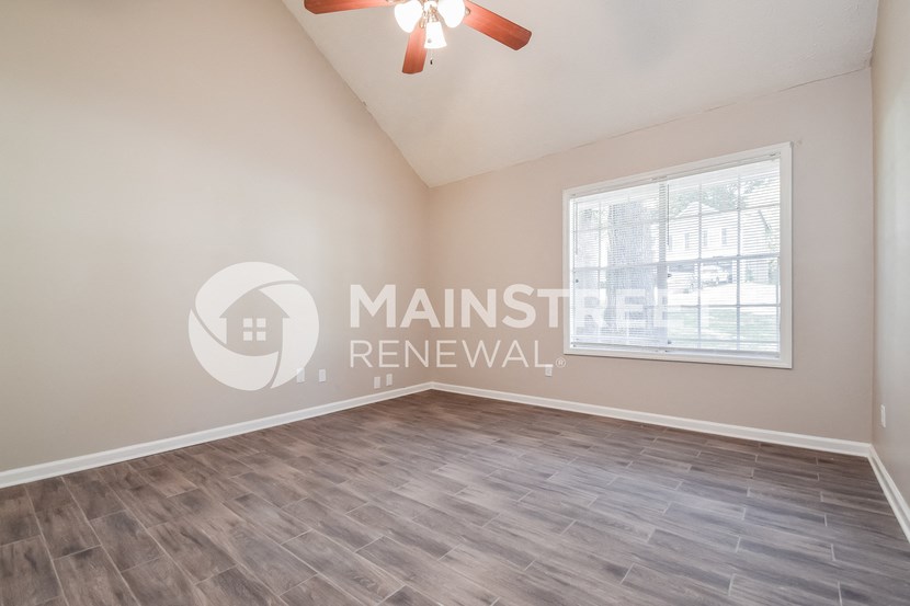 a room with a large window and a ceiling fan