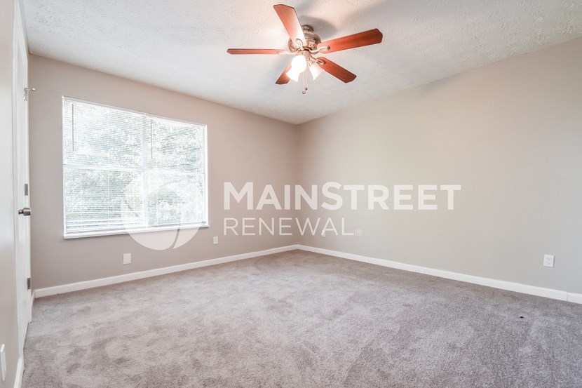 an empty living room with a ceiling fan and a window
