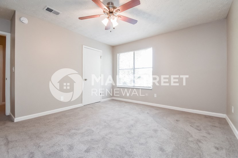 an empty living room with a ceiling fan and a window