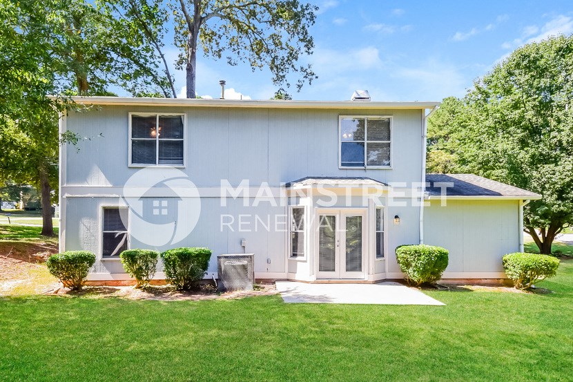 a small blue house with a lawn and trees