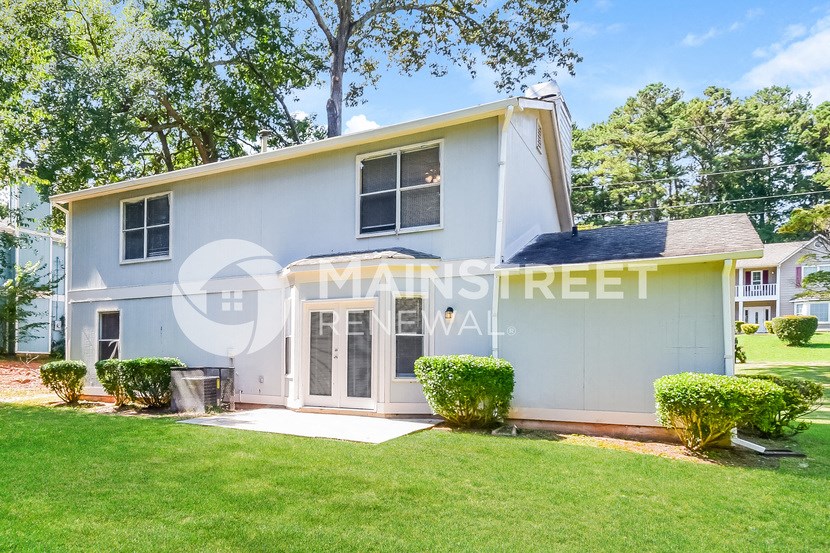 a small blue house with a lawn and trees