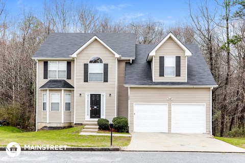 a tan house with a gray roof and a white garage door