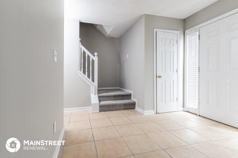 the entryway of a home with a staircase and a white door