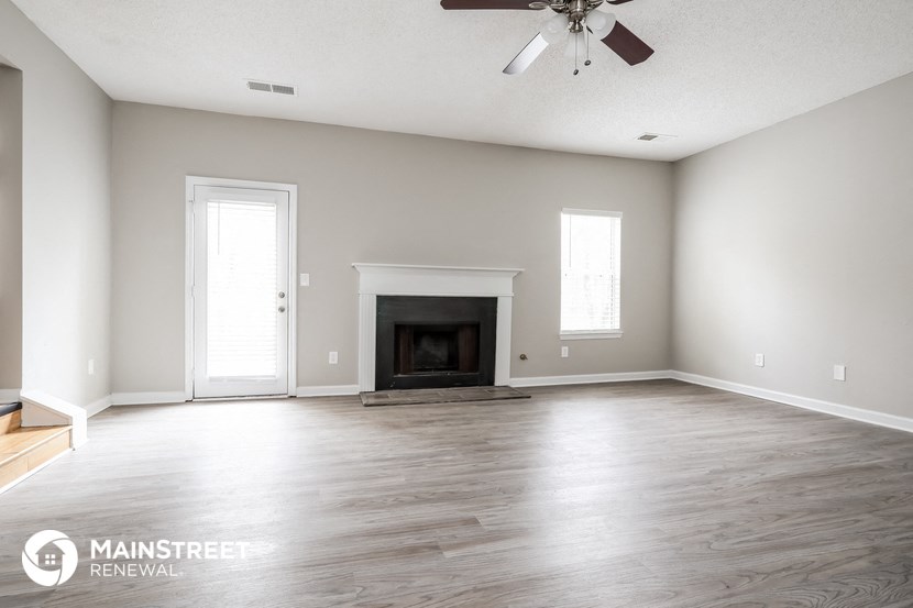the living room with wood floors and a fireplace
