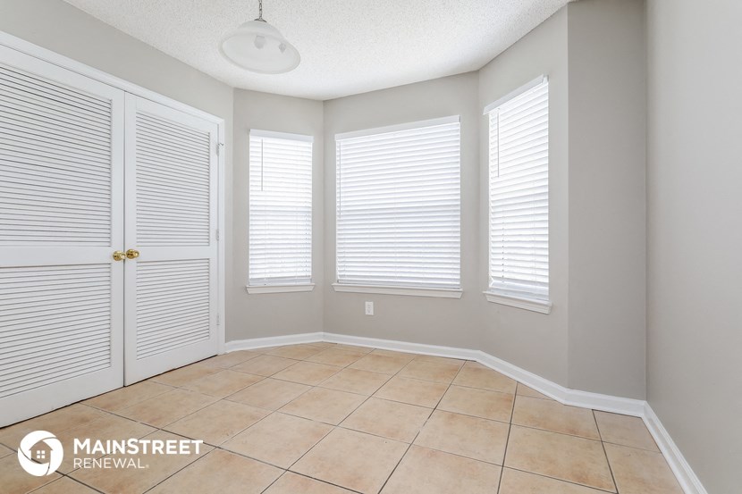 a dining room with white shuttered windows and a tiled floor