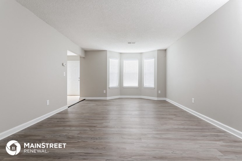 the spacious living room with wood floors and white walls