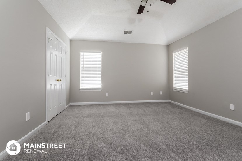the spacious living room with carpeted flooring and white doors