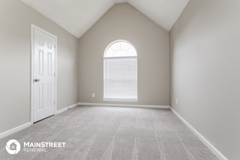 the master bedroom has a large window and carpeted flooring