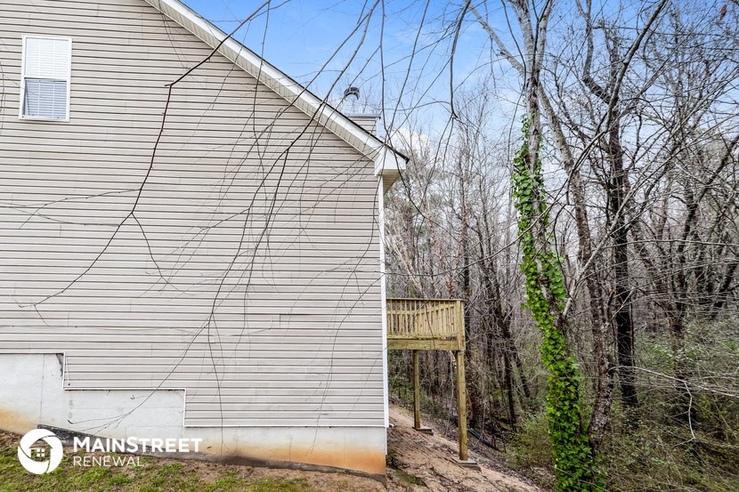 the side of a house with a fence and a tree