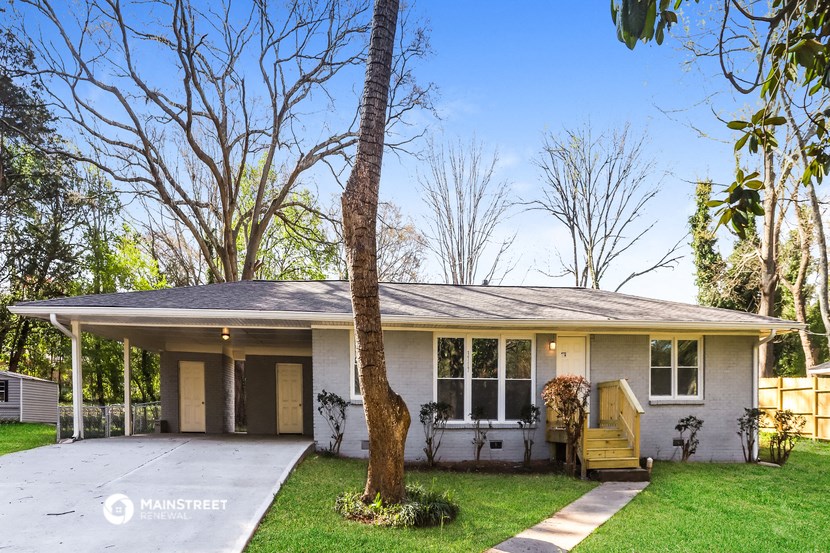 a white house with a porch and a tree