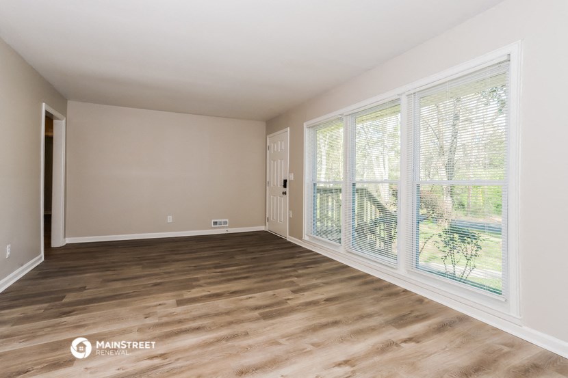 an empty living room with large windows and wood flooring