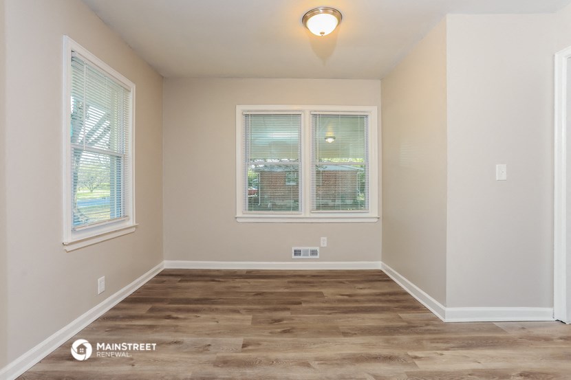 the spacious dining room with hardwood flooring and two windows
