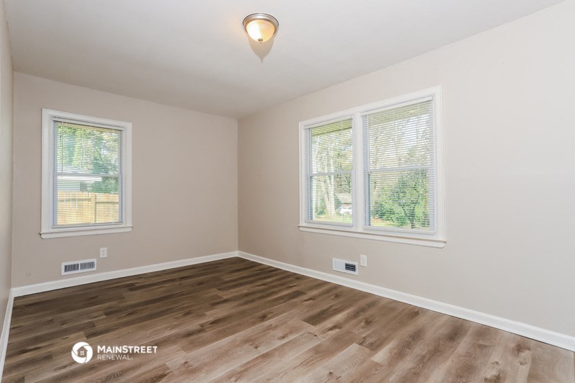 the spacious living room with hardwood flooring and two windows