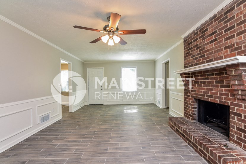a living room with a brick fireplace and a ceiling fan
