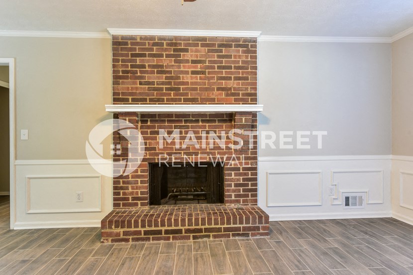 a living room with a brick fireplace and a wooden floor