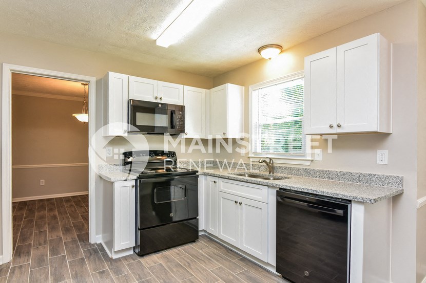 a kitchen with white cabinets and black appliances and a counter top