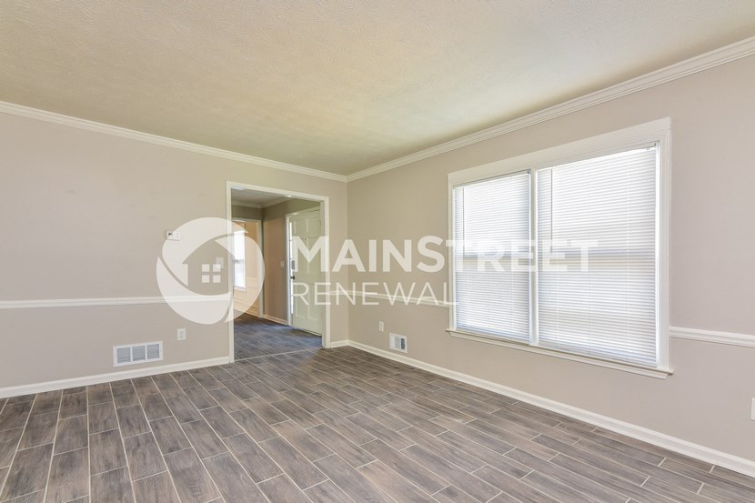 a bedroom with a large window and a hard wood floor