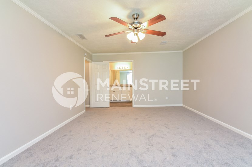a living room with a white carpet and a ceiling fan