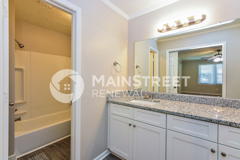 a bathroom with white cabinets and a sink and a mirror