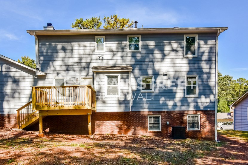the side of a house with a deck and the shadows of a tree
