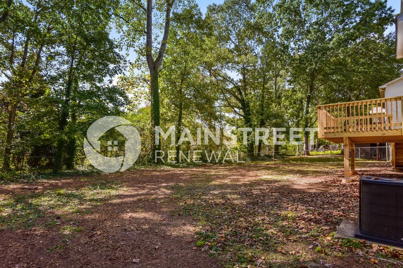 a large yard with a deck and a cabin in the woods