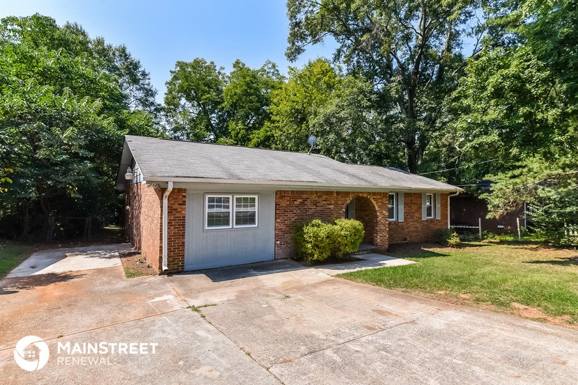 a small brick house with a garage and a driveway