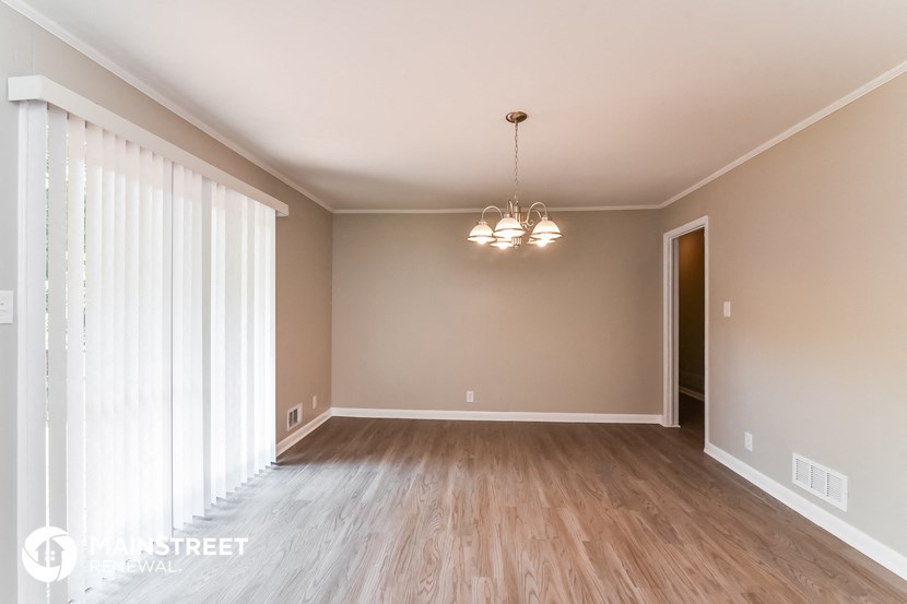 an empty living room with wood floors and a large window