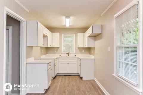 a white kitchen with white cabinets and a window